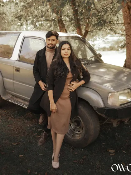 A stylish couple posing with a vintage SUV in a rustic setting, perfect for a unique and adventurous pre-wedding theme.