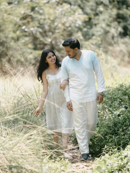 A couple walks arm-in-arm through a grassy path in Coorg, capturing a natural and romantic moment.