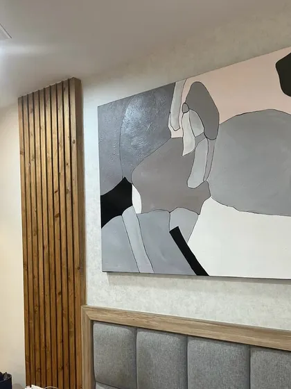 A 5ft x 4ft abstract painting installed above a headboard in a Bangalore bedroom. The soft grey, pink, and black palette creates a restful yet modern atmosphere.