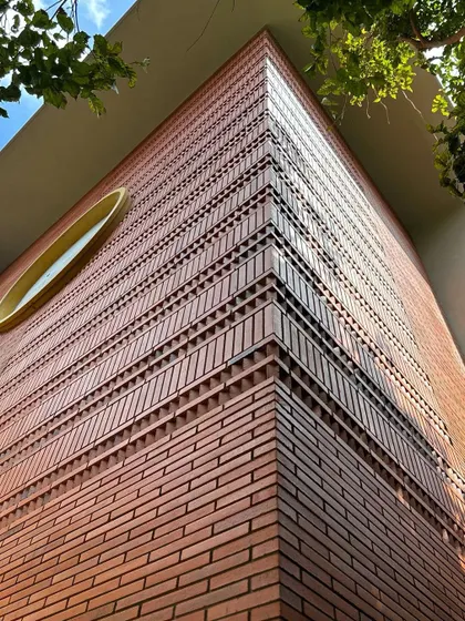 An upward view of the detailed brickwork on a building corner. We use intricate patterns and textures in our brick facades to create visual interest and celebrate the beauty of the material itself.