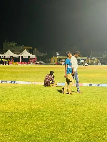 Spectators enjoying a night match from the boundary, a testament to the exciting atmosphere we create for cricket events.