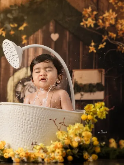 Splash time fun. This toddler enjoys a playful bath in a rustic tub, surrounded by yellow flowers and rubber ducks.