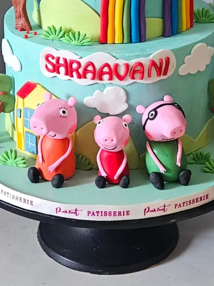 A detail shot of the bottom tier of the Peppa Pig cake, featuring hand-sculpted figurines of Mummy Pig, Daddy Pig, and Peppa's house.