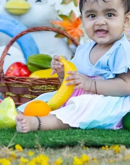 A happy baby enjoying some fruit props during her outdoor shoot. These little details add color and a sense of play to the photographs.