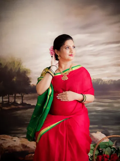 A duplicate of image 164, this serene portrait shows a mom-to-be in a traditional red and green saree, cradling her bump.