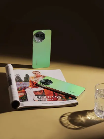 A product shot of the realme C67, using dramatic shadows and a magazine to create a sophisticated, editorial feel.