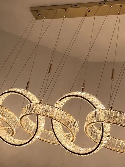 This luxury LED pendant features five interlocking rings of crystal. It's a glamorous and modern chandelier perfect for hanging over a long dining table, providing brilliant, sparkling light.