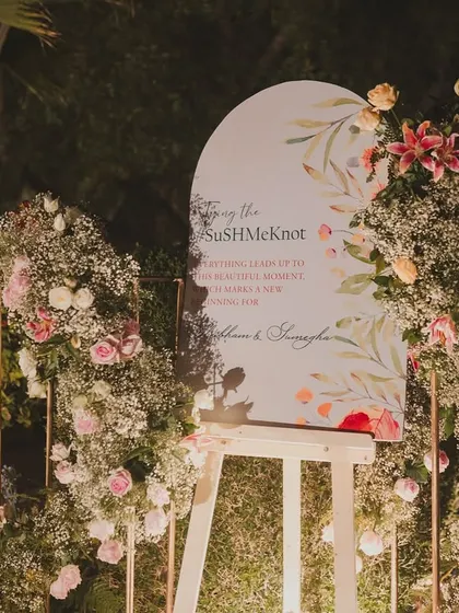 A floral welcome sign for the "SuSHMeKnot" wedding, surrounded by an abundance of baby's breath and pastel roses, creating a soft and romantic first impression.