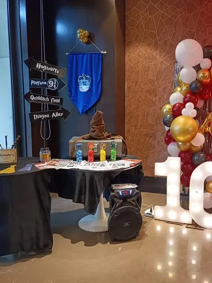 We transform any space into a wizard's workshop. This setup for a 10th birthday includes a sorting hat station, house banners, and a backdrop for a truly immersive experience.