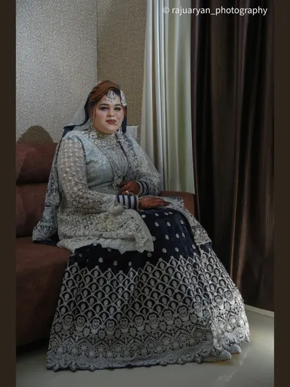 A full-length portrait of the bride seated, allowing her elaborate lehenga to be displayed beautifully. This formal pose has a regal and timeless quality.