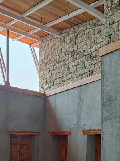 **Haat Market, Shyamlatal:** The interior view shows the combination of exposed stone walls and a wooden ceiling. A clerestory window brings in natural light, illuminating the space where local products will be displayed.