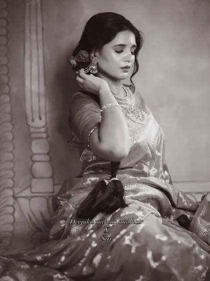A candid, thoughtful pose in black and white, highlighting the elegant hairstyle and the drape of the saree.