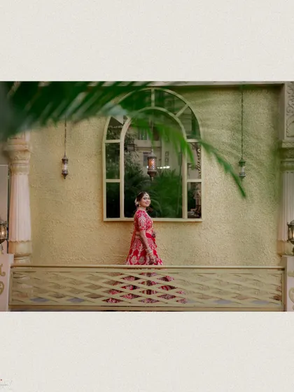 A creative shot of the bride on a balcony, framed by a palm leaf.