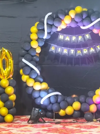A different style for a 50th birthday, this setup uses a full balloon ring in black and yellow with large foil numbers on a separate pillar.