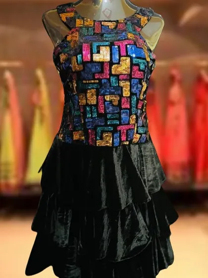 This short black dress features a tiered velvet skirt and a bodice covered in colorful, geometric sequins. It's a unique and playful choice for a night out.