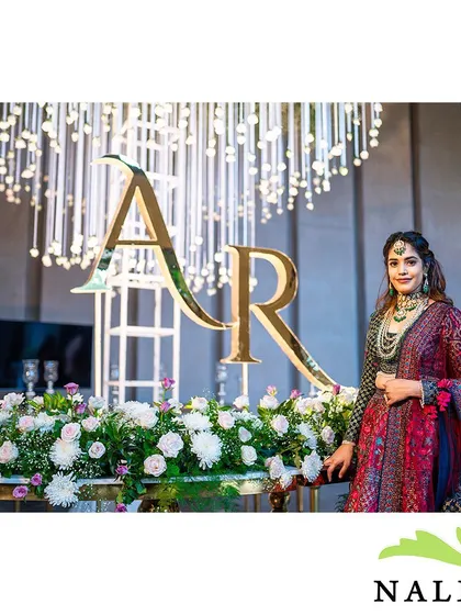The bride poses by the magnificent floral and monogrammed setup. This shows how my decor creates stunning backdrops for the most important photos of the day.