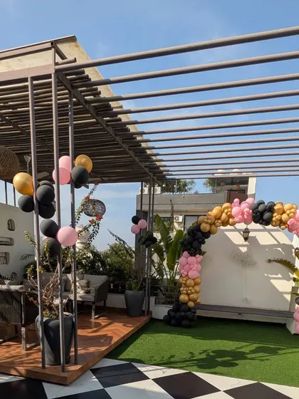 This image shows the full context of the terrace party setup, with the balloon arch as the main feature in a beautiful outdoor seating area.