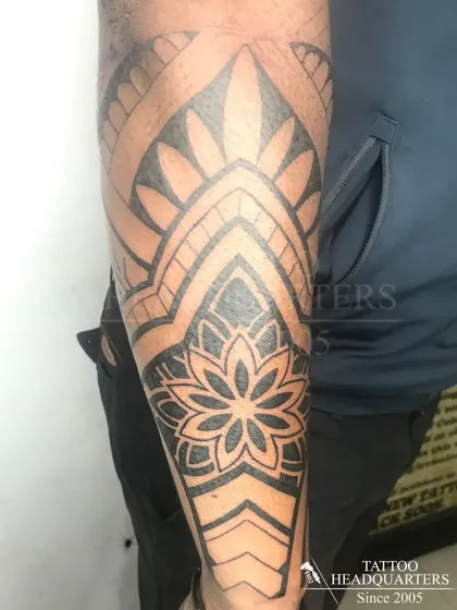 A half-sleeve tattoo featuring a large mandala and other geometric patterns, creating a cohesive and intricate design.