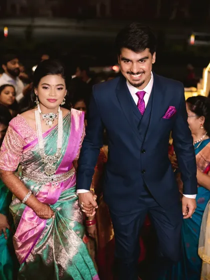 The couple walking hand-in-hand. The bride's makeup is flawless and her diamond jewelry adds a touch of sparkle.