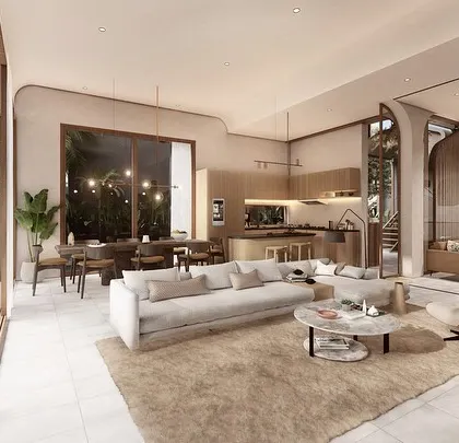 The interior of a Vagator villa showcases an open-plan living, dining, and kitchen area with earthy finishes and soft, neutral tones. Large sliding glass doors connect the space directly to the pool deck, promoting a relaxed, indoor-outdoor lifestyle.
