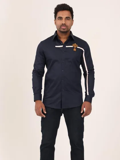 This navy blue shirt is a study in refined detail, featuring a clean white stripe accent and a hand-embroidered golden crest. It’s a perfect choice for a polished, regal look that speaks of quiet confidence.