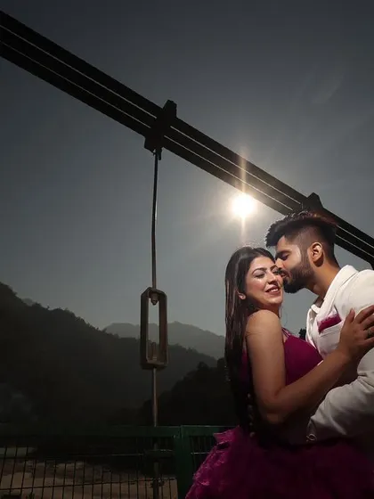 A beautiful silhouette shot against the setting sun on a bridge in Rishikesh. This technique creates a timeless and romantic image, focusing on the couple's embrace and the stunning natural scenery.
