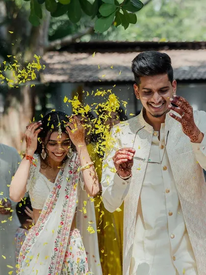A shower of yellow petals marks a moment of pure joy for the couple as they walk through their Haldi celebration.