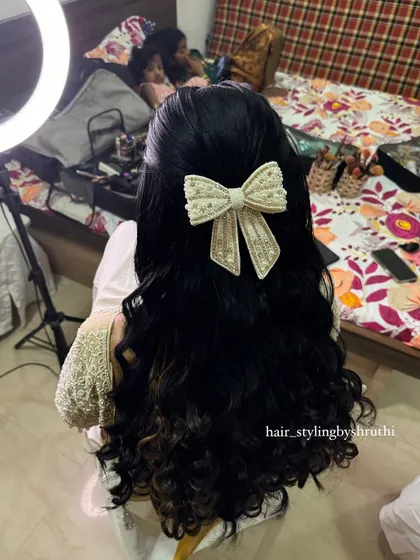 A half-up style with soft waves, secured with a large, embellished bow. This look is both sweet and sophisticated, perfect for an engagement or reception.