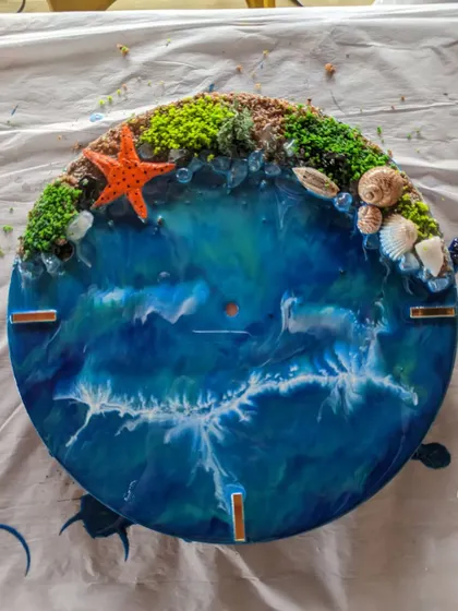 A stunning, finished resin beach clock, complete with realistic waves, a sandy shore, and decorative shells and starfish.