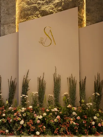 Modern elegance is one of our signatures. This chic Roka ceremony backdrop features a clean, multi-panel design with a custom gold monogram and a wildflower-inspired floral base, perfect for a sophisticated celebration.