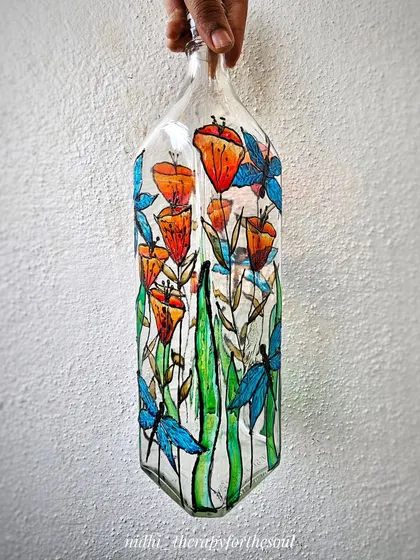 This design features orange Kanakambari flowers and blue dragonflies on a clear bottle, creating a beautiful stained-glass effect. I love the contrast between the warm orange and cool blue tones.