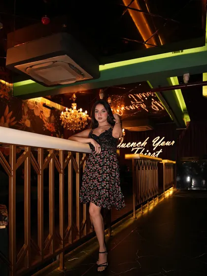 A lifestyle shot of a model in a floral dress inside a dimly lit, elegant cafe. This shows how I work with interior lighting to create atmosphere.