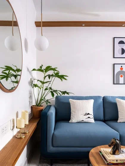 A close-up of the living area in the 'Footloose' studio apartment, showing a comfortable blue sofa, a round wooden mirror, and carefully chosen decor. This space is designed to feel clean, modern, and homely.