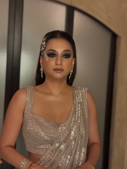 The client looks stunning in her sequined saree. The sleek, straight hair with the side accessory is a modern take on event hair, perfect for a high-fashion look.