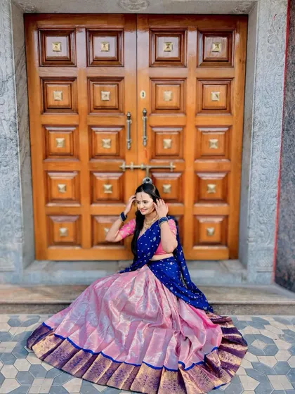 A happy client seated in a beautiful pink and royal blue silk Langa Voni. The rich texture of the silk skirt shines, making it perfect for photos.