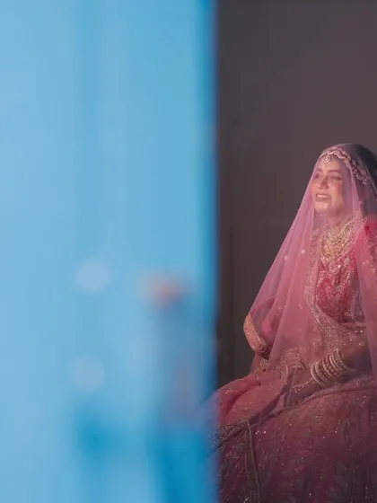 A creative shot of the bride seen through a blue doorway, creating a beautiful frame and a sense of looking in on a private, happy moment.