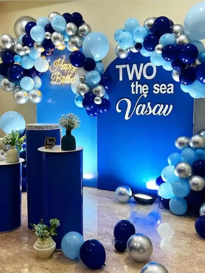 A "Two the Sea" ocean-themed second birthday. This elegant setup uses shades of blue and silver balloons to create waves over custom blue backdrops.