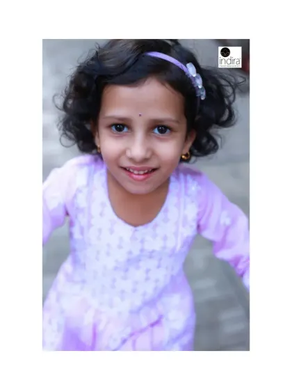 A candid shot filled with energy and movement. The slight blur and her direct gaze create a dynamic and engaging portrait that captures the feeling of being a happy, active child.