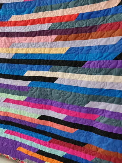 A close-up of the jelly roll race quilt, showing the variety of colors and the floral quilting pattern.