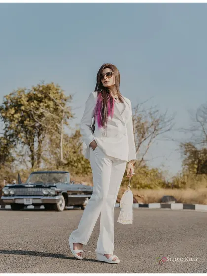 A confident and stylish portrait of the bride-to-be in a white suit with a vintage car in the background. This shot has a strong, independent, and fashionable feel.