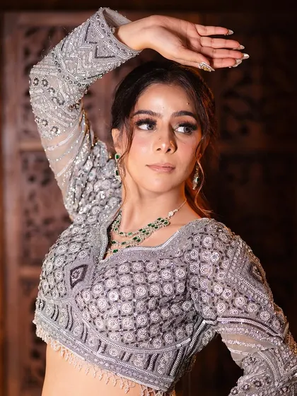 A graceful pose showing the intricate work on the full-sleeve blouse. This is a perfect outfit for a winter wedding event.