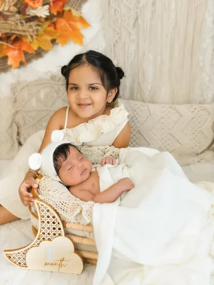 One month old and already so loved. Including older siblings in newborn milestone shoots creates such precious memories, like this sweet moment with big sister smiling for the camera.