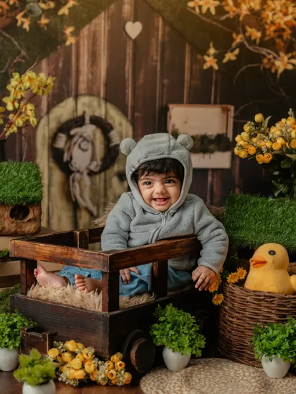 A cozy and cute teddy bear theme, with a smiling baby in a wooden cart surrounded by greenery.