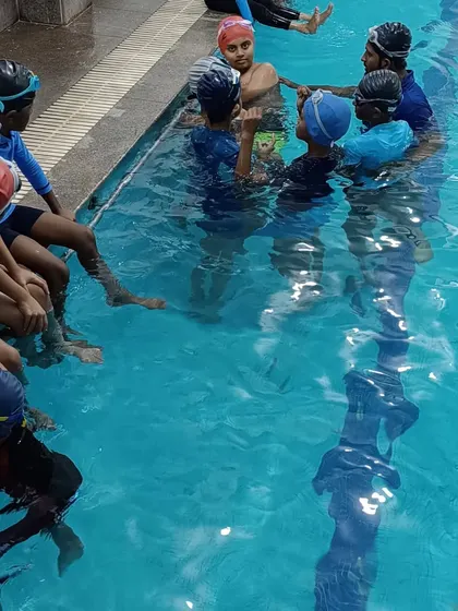 A group of students gathered in the water for a lesson, highlighting the social aspect of our swim camps.
