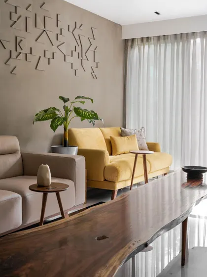 **Achrome, Ahmedabad:** A custom art installation on a lime-plastered wall adds texture and a point of interest. The use of a live-edge wooden table brings an organic, natural element into the refined interior, balancing clean lines with raw beauty.