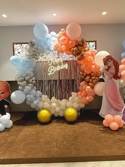 A fun birthday setup for twins, combining Boss Baby and Disney Princess themes with a colorful balloon ring and character cutouts.