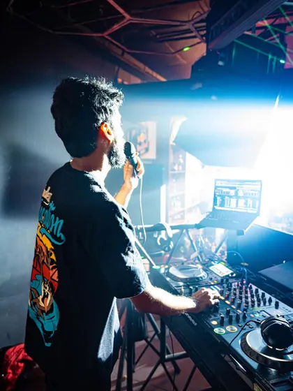 On the mic, interacting with the crowd under a bright spotlight.