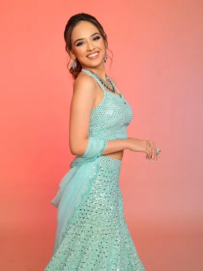 A smiling portrait in the pastel blue lehenga, with makeup that is fresh, glowing, and perfect for a summer event.