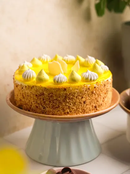 A full view of a stunning mango cake on a pastel blue stand. This shot highlights the beautiful piping work and crumb coating, presenting it as a perfect centerpiece for any celebration.
