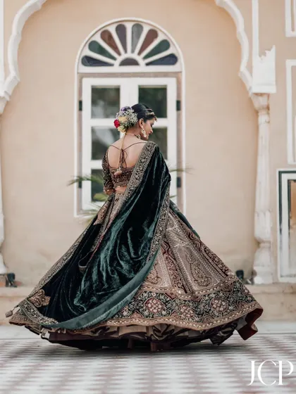 A full-length shot of the bride in a magnificent velvet lehenga, twirling in the courtyard of Chomu Palace, Jaipur.